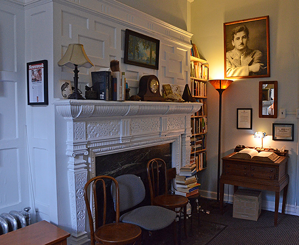 0verview of office from desk area, angled toward fireplace & door; portrait of Faulkner above lighted unabridged dictionary on table