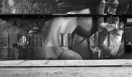 Photograph of street art of a woman’s neck and hand in a realistic style.